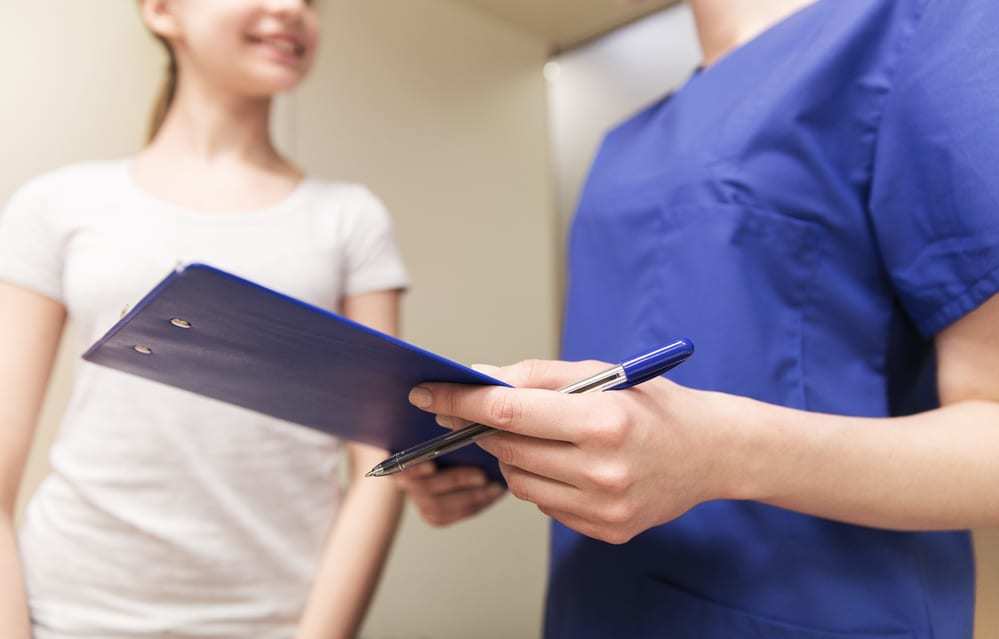 Close-up of nurse with clipboard and young girl